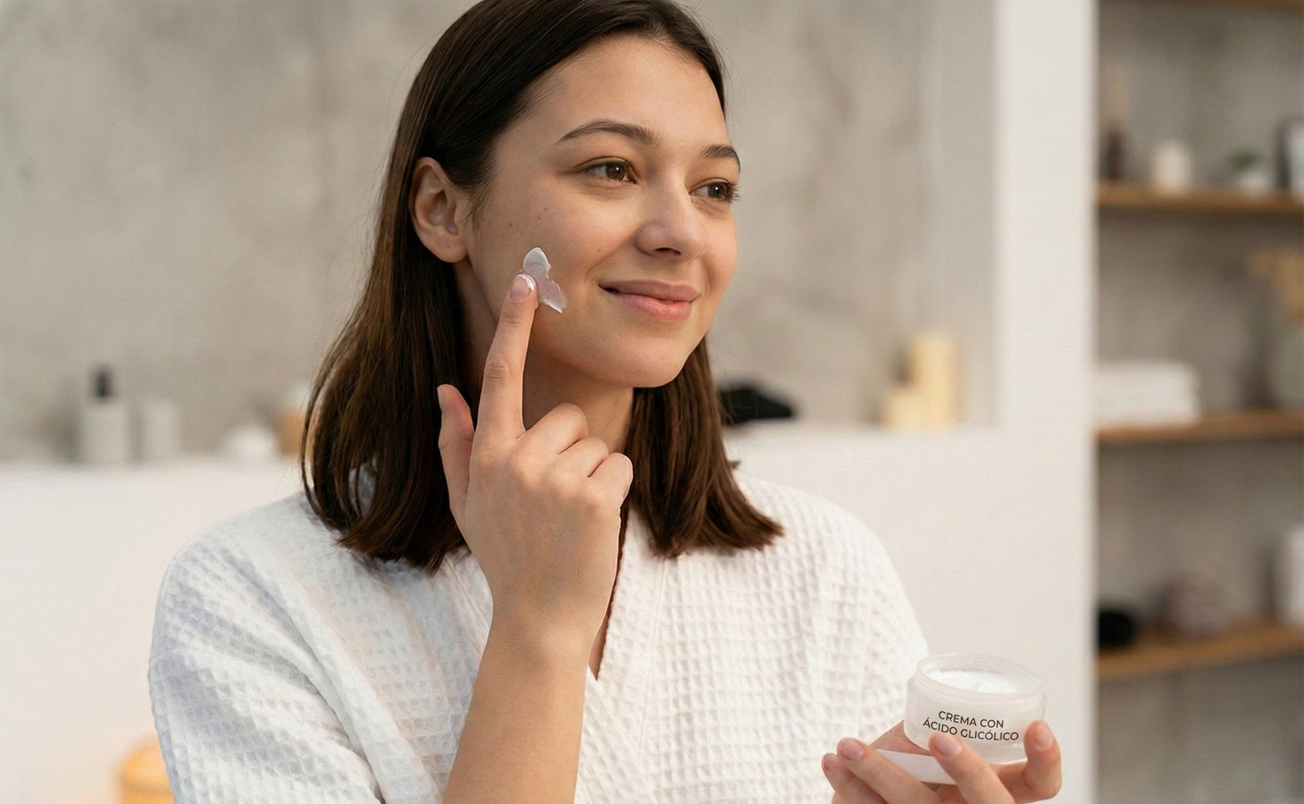 Mujer aplicando crema con ácido glicólico, activo dermatológico que mejora textura, luminosidad y renovación de la piel.